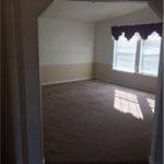 Entry into carpeted living room with large windows